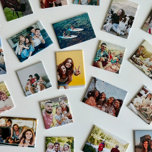 Colorful custom photo magnets by Milestone Magnets scattered on white, capturing beach trips, puppy love, family, and celebrations as magnetic keepsakes.